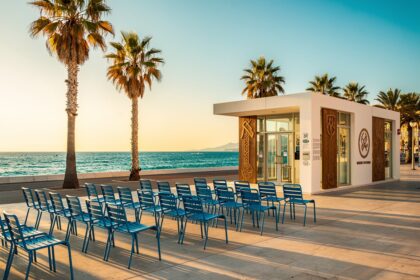La Promenade des Anglais à Nice au coucher du soleil avec ses chaises bleues et palmiers face à la Méditerranée.
