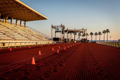 Piste de trot rouge de l'hippodrome au coucher du soleil avec scène de festival en construction au fond