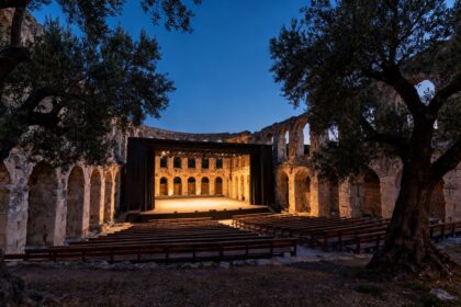 Scène de théâtre en plein air dans les ruines d'un amphithéâtre romain au crépuscule, entourée d'oliviers