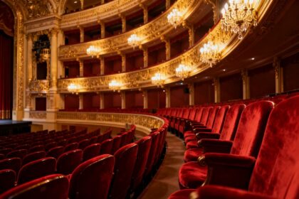 Salle à l'italienne d'un opéra, fauteuils en velours rouge et balcons dorés éclairés avant une représentation