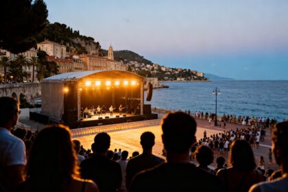 Scène de concert en plein air sur une esplanade en bord de mer, lumières chaudes au crépuscule