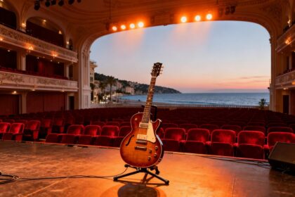 Scène d'un grand auditorium au crépuscule, guitare électrique posée sur un pied sous des projecteurs chauds