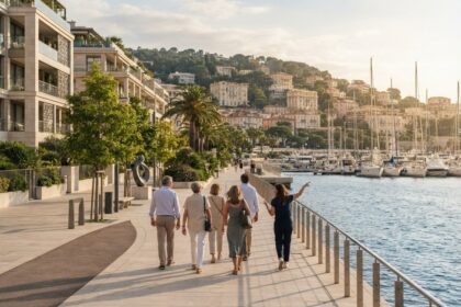 Un petit groupe de visiteurs suit une guide sur une promenade en bord de mer, face à un port de plaisance