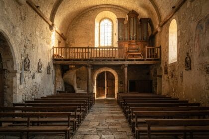 Orgue à tuyaux sur une tribune en bois au-dessus de l'entrée d'une petite église de village en pierre