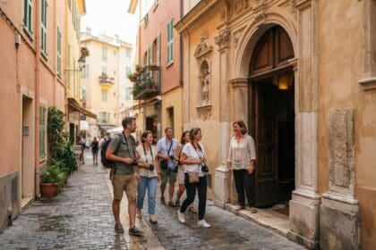 Un groupe de visiteurs remonte une ruelle pavée du Vieux-Nice vers le portail baroque ouvert d'une chapelle